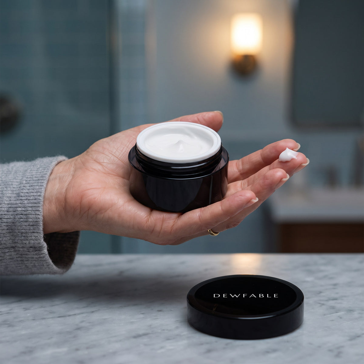 Active Eye Cream jar in the hand with a dab on the ring finger