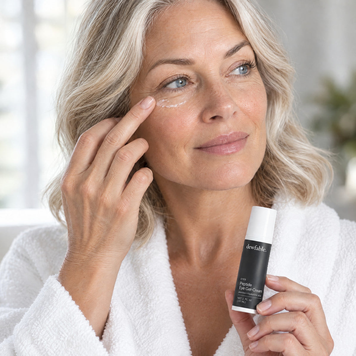 A woman in her fifties patting dewfable. Peptide Eye Gel-Cream under her eye